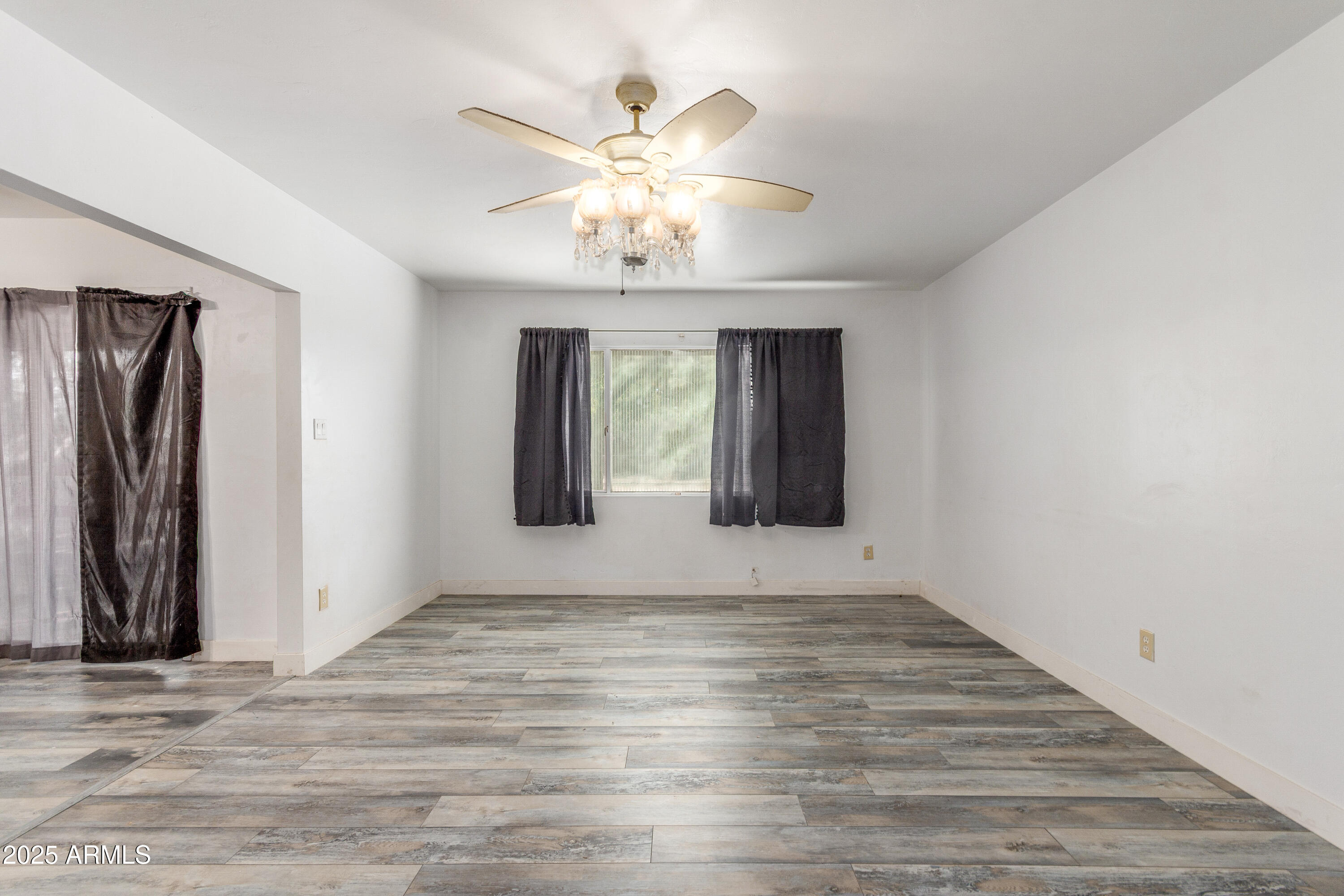 413 East 3rd Street Eloy, AZ 85131 - Photo 8 of 44 a view of an empty room with wooden floor and a ceiling fan