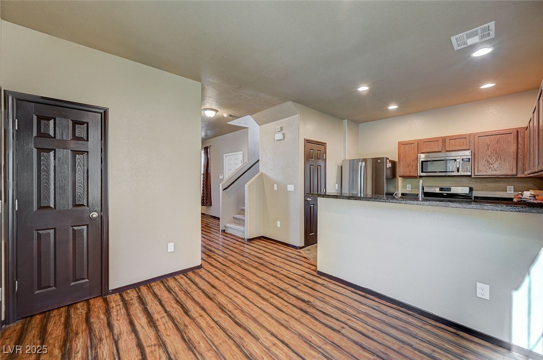971 Sable Chase Place Henderson, NV 89011 - Photo 11 of 48 Kitchen with brown cabinetry, LVP floors, breakfast bar, and SS appliances