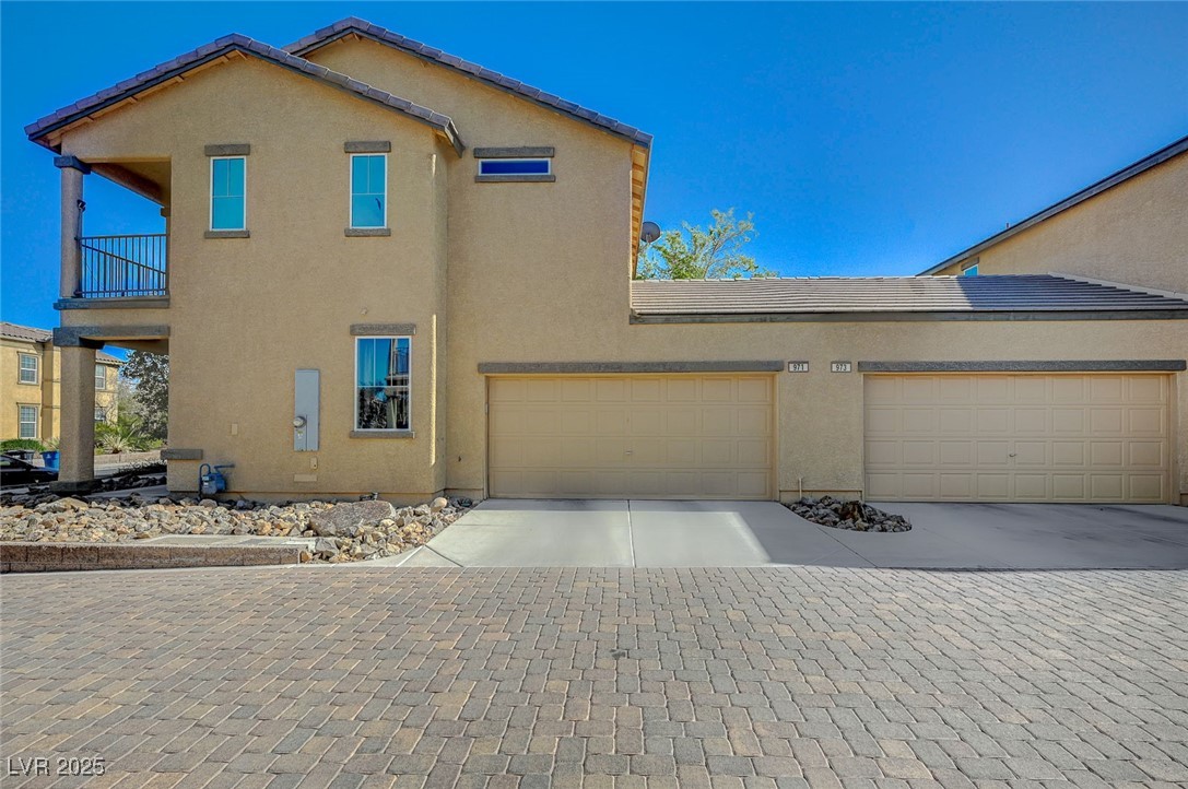 971 Sable Chase Place Henderson, NV 89011 - Photo 3 of 48 View of side of home featuring garage, a tile roof, paver driveway, and a balcony
