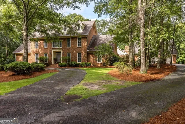 a front view of a house with a yard and tree s