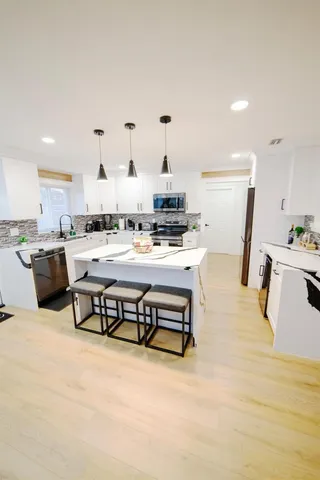 a kitchen with stainless steel appliances kitchen island granite countertop a table chairs sink and cabinets