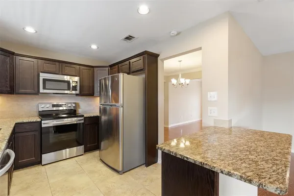 a kitchen with stainless steel appliances granite countertop a refrigerator a stove and a sink