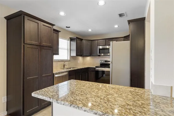 a kitchen with granite countertop stainless steel appliances a refrigerator and microwave