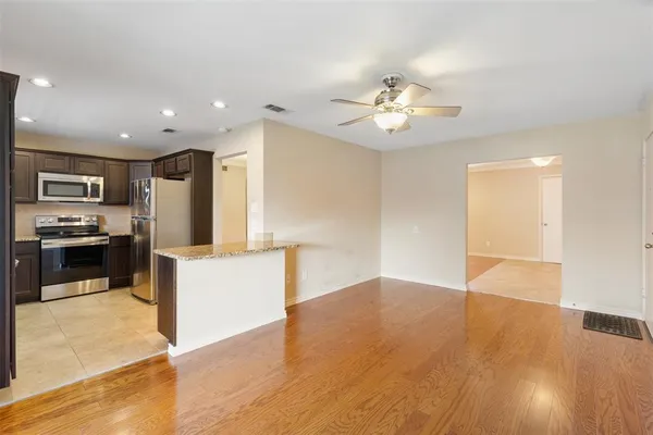 a view of kitchen with cabinets stainless steel appliances and a ceiling fan