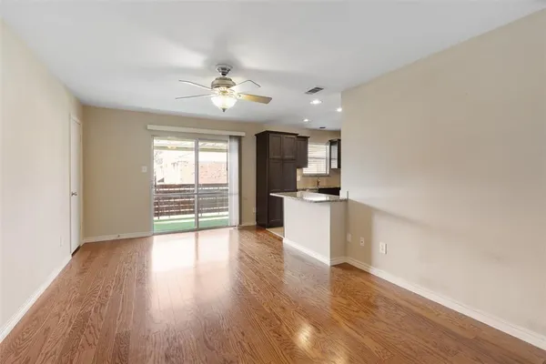 a view of an empty room with a window and wooden floor