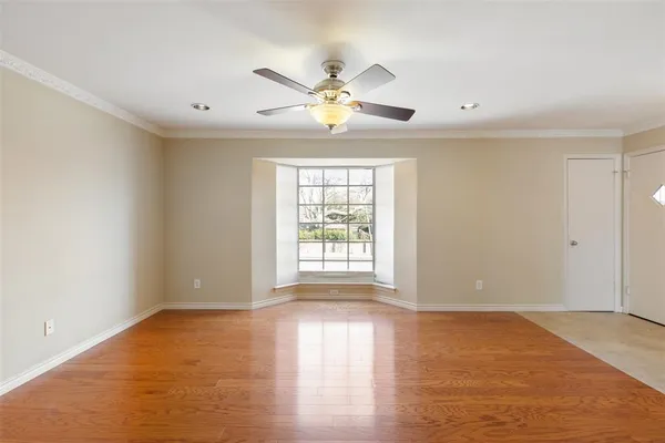 a view of an empty room with window and wooden floor