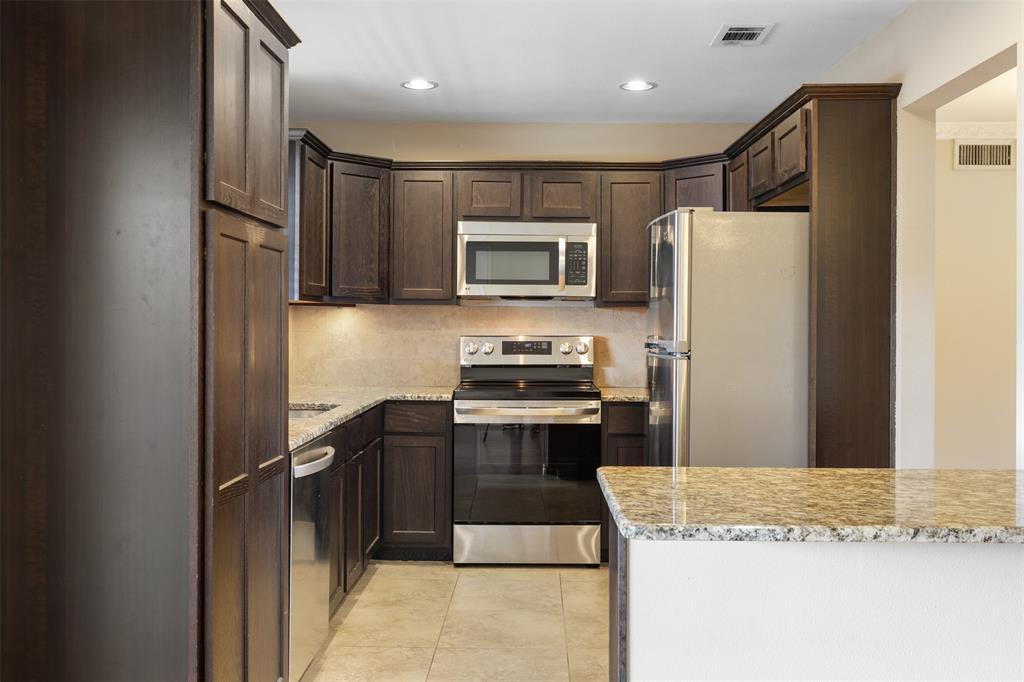4709 Skillman Street, Unit D Dallas, TX 75206 - Photo 9 of 28 a kitchen with granite countertop stainless steel appliances and wooden cabinets