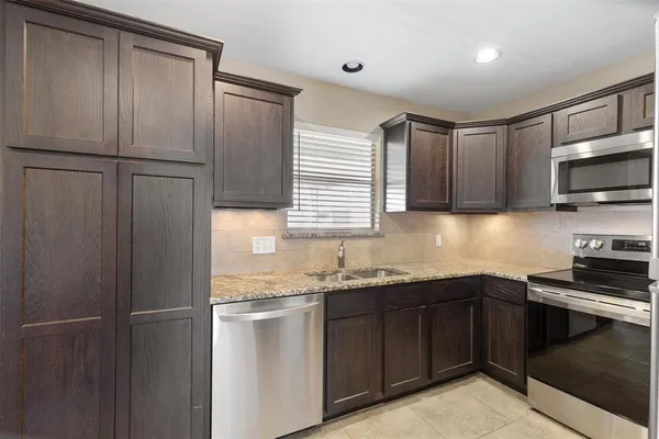 a kitchen with stainless steel appliances granite countertop a refrigerator a sink dishwasher a stove and white cabinets
