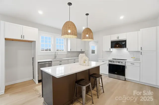 a kitchen with stainless steel appliances granite countertop a sink a stove and a wooden floors