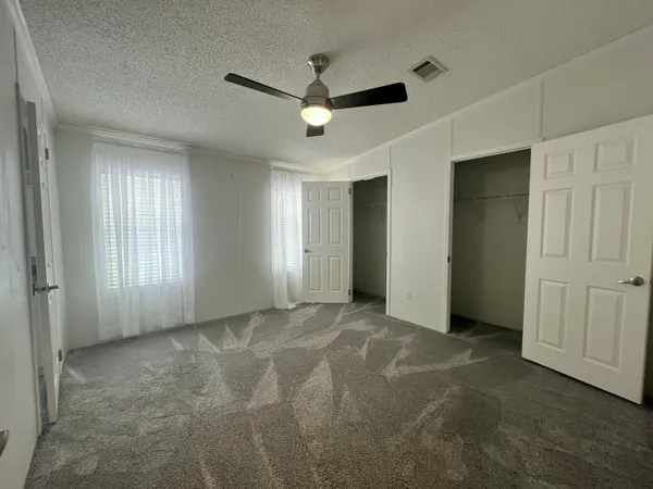 a view of a livingroom with a ceiling fan & windows