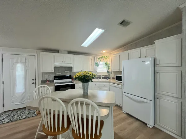 a kitchen with stainless steel appliances a refrigerator a stove a dining table and chairs