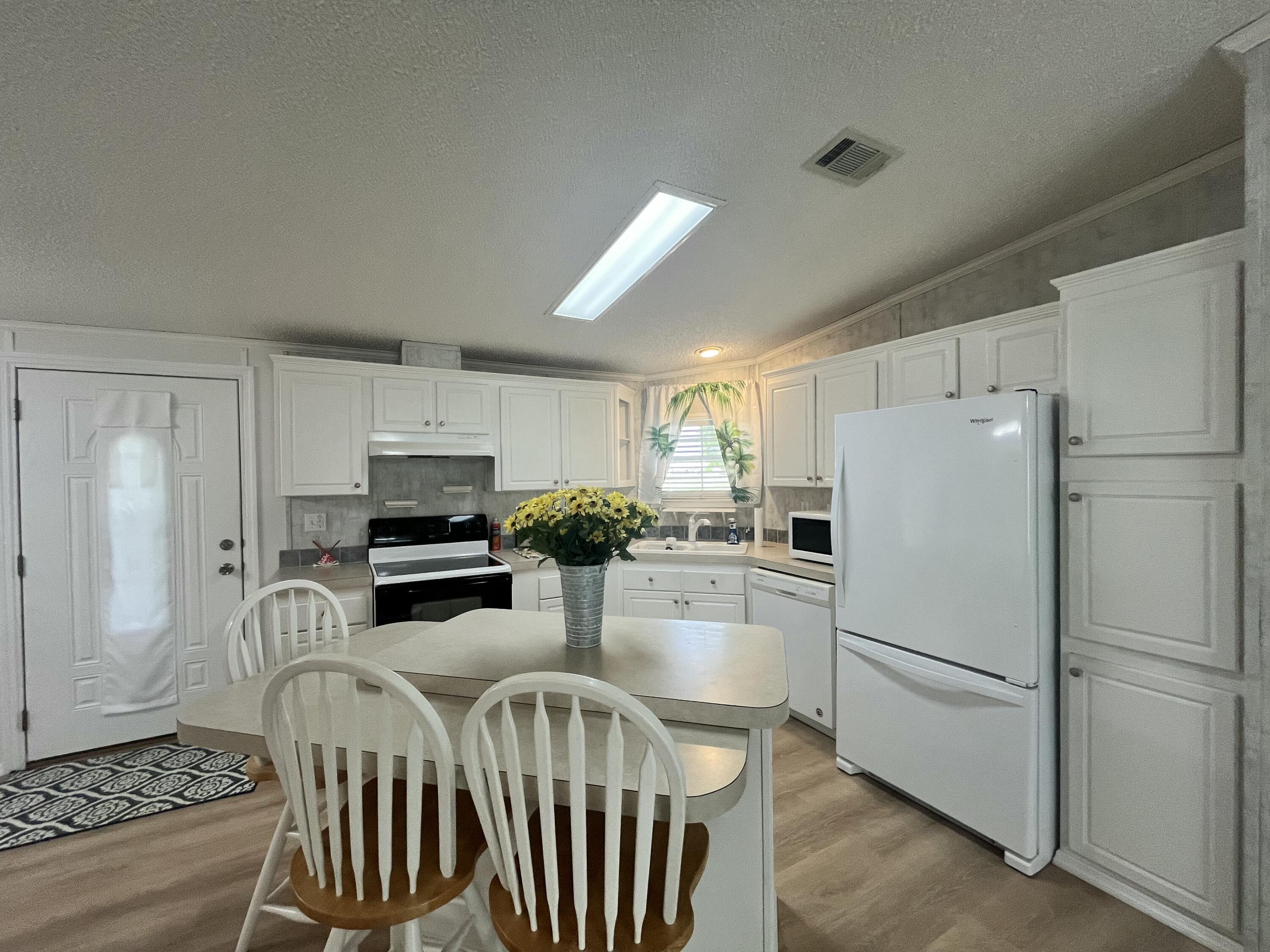 4064 Southwest 9th Way Okeechobee, FL 34974 - Photo 3 of 39 a kitchen with stainless steel appliances a refrigerator a stove a dining table and chairs