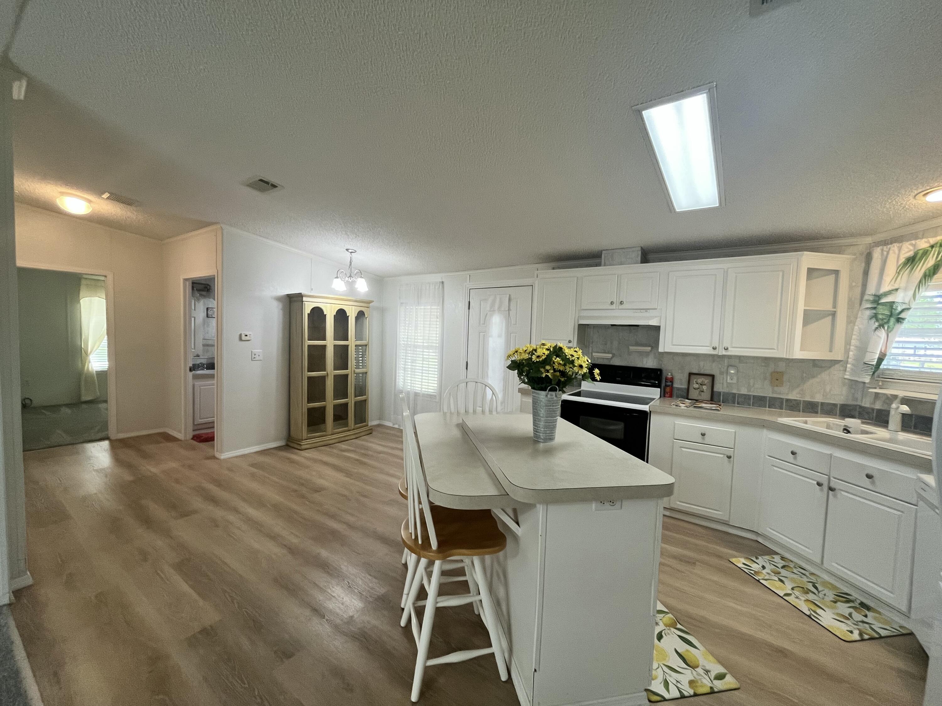 4064 Southwest 9th Way Okeechobee, FL 34974 - Photo 4 of 39 a kitchen with a table chairs refrigerator and microwave