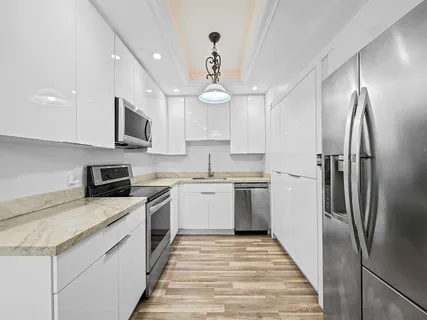 a kitchen with a sink stainless steel appliances and white cabinets