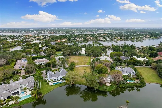 an aerial view of residential houses with outdoor space and lake view in back