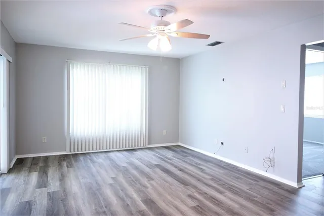 a view of an empty room with wooden floor and a window