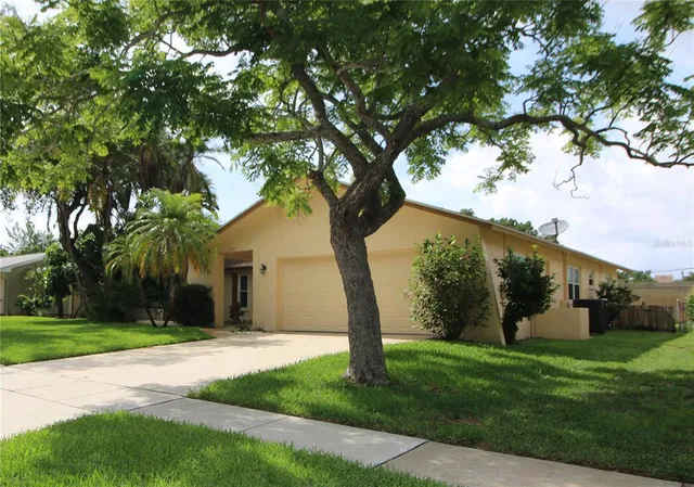 a view of a white house with a big yard and large tree
