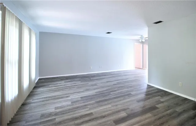 a view of an empty room with wooden floor and a window