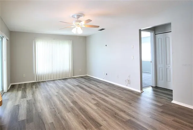 an empty room with wooden floor and windows