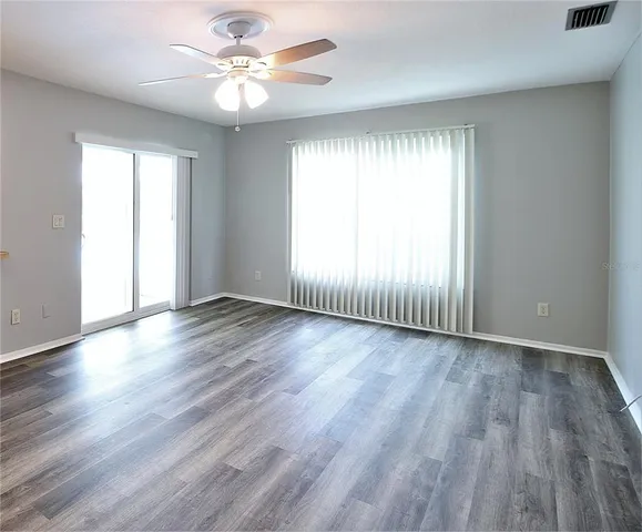 an empty room with wooden floor and windows