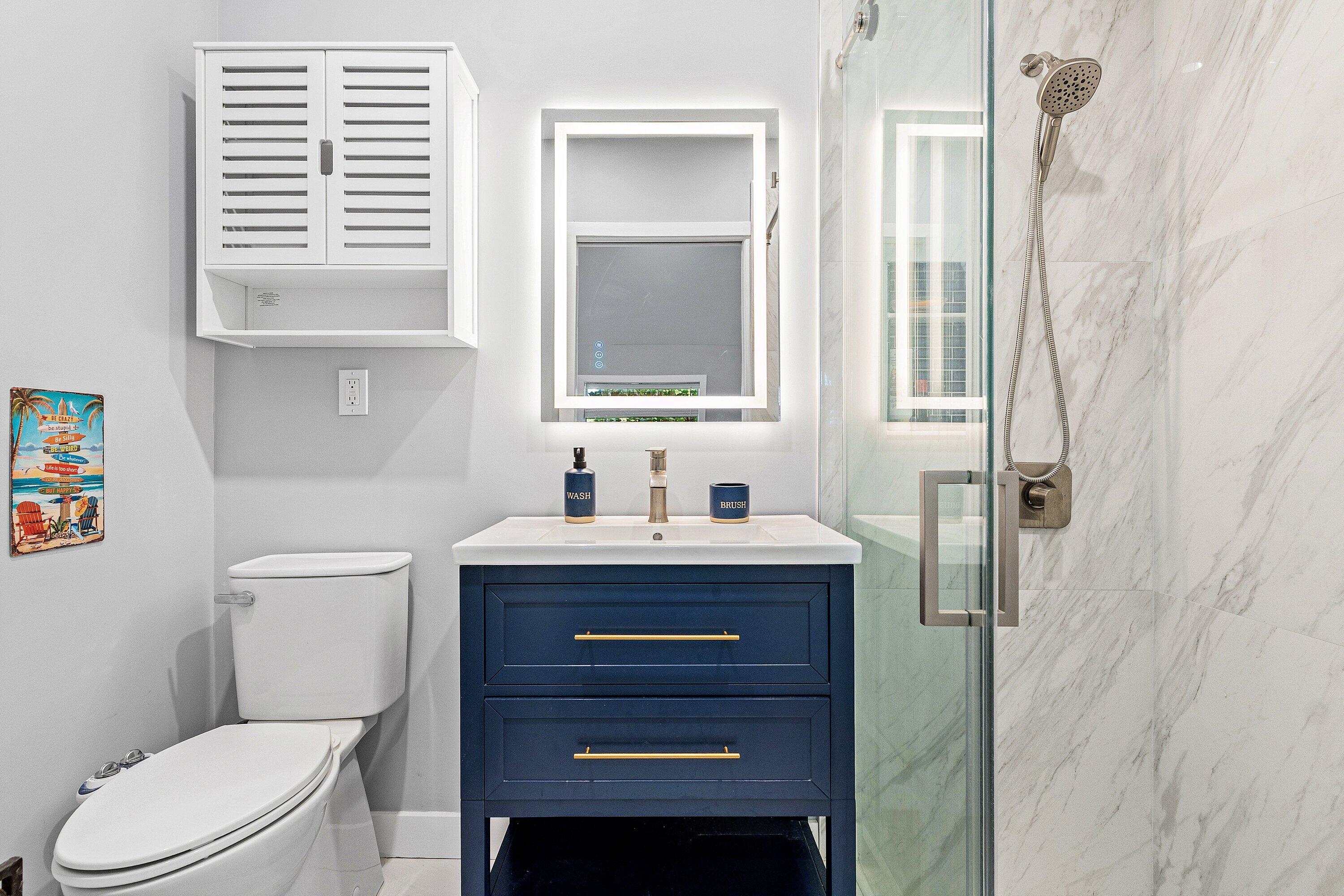 72 South Ocean Boulevard, Unit 1 Delray Beach, FL 33483 - Photo 17 of 35 a bathroom with a toilet a sink a vanity a window and mirror