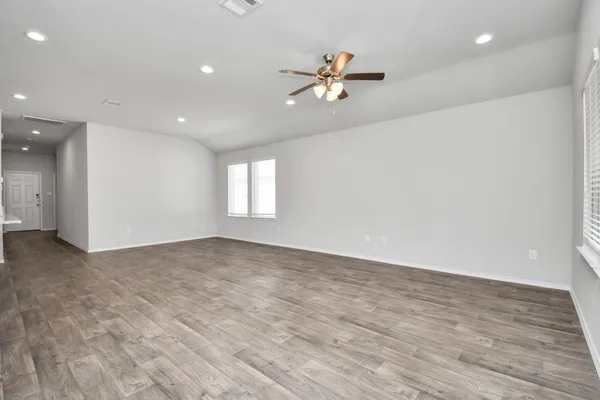 a view of an empty room with window and wooden floor