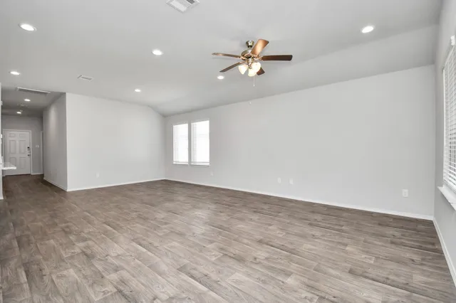 a view of an empty room with window and wooden floor