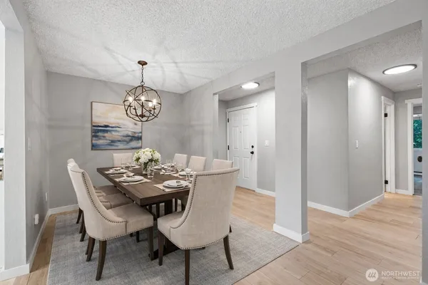 an empty room with wooden floor and kitchen view
