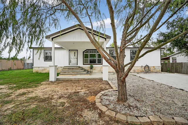 a white house that has a tree in front of the house