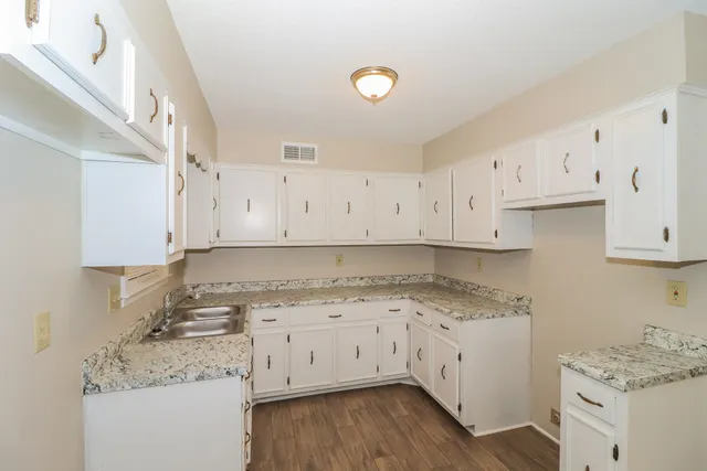 a kitchen with granite countertop a sink a stove and cabinets