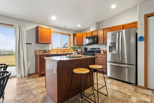 a kitchen with stainless steel appliances granite countertop a refrigerator a stove a sink a microwave and a refrigerator