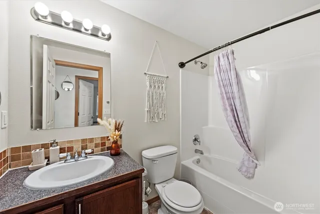 a bathroom with a granite countertop sink toilet a mirror a vanity and shower