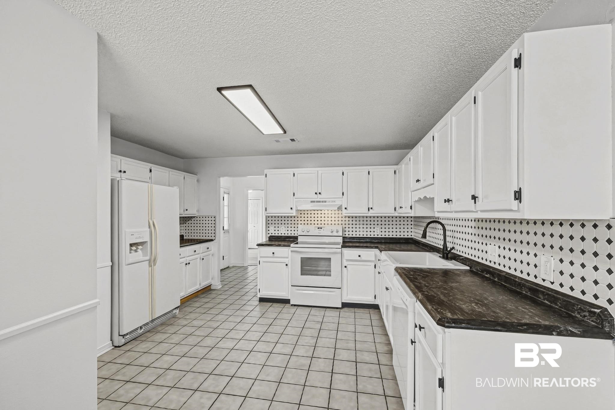2776 Santa Rosa Circle Lillian, AL 36549 - Photo 10 of 48 Kitchen with dark countertops, white appliances, white cabinets, decorative backsplash, and a textured ceiling