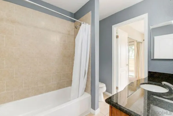 a bathroom with a granite countertop sink and a bathtub