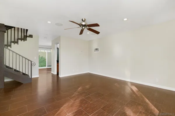 an empty room with wooden floor ceiling fan and windows
