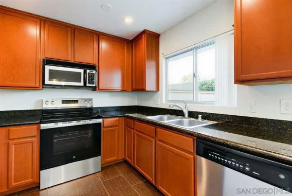 a kitchen with granite countertop cabinets stainless steel appliances a sink and window