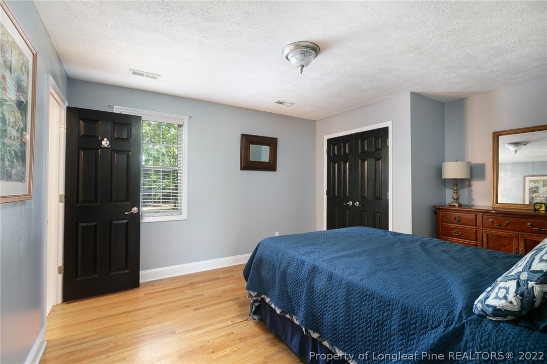 5016 J T Matthews Road Godwin, NC 28344 - Photo 23 of 50 a bedroom with a bed and wooden floor