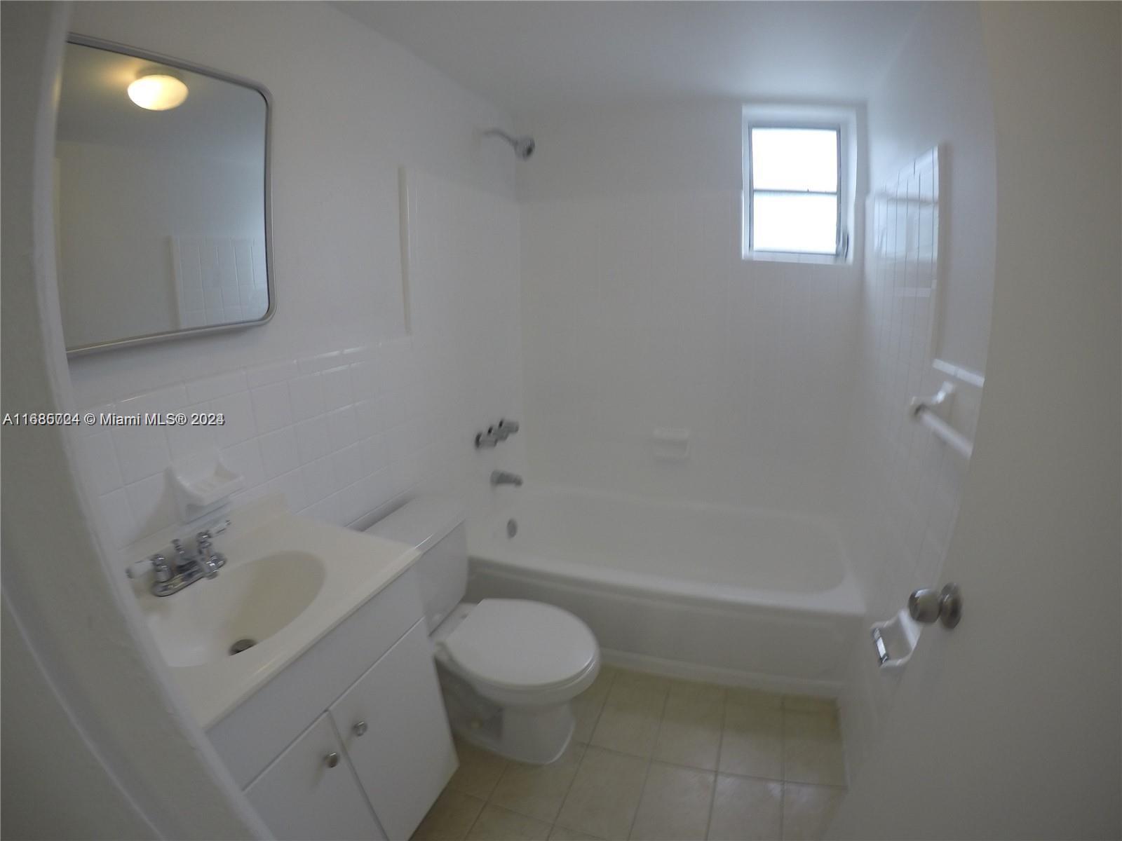 1828 Northwest 19th Street, Unit 4 Miami, FL 33125 - Photo 7 of 22 a bathroom with a toilet a sink a mirror and bathtub
