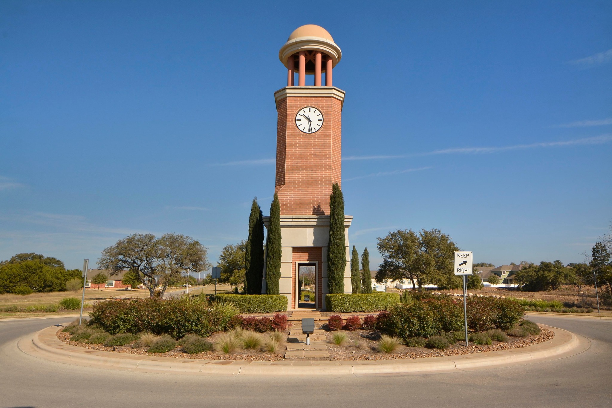 1818 Lost Maples Loop Cedar Park, TX 78613 - Photo 33 of 38 A stately clock tower rises from a meticulously landscaped roundabout, marking a grand entrance.