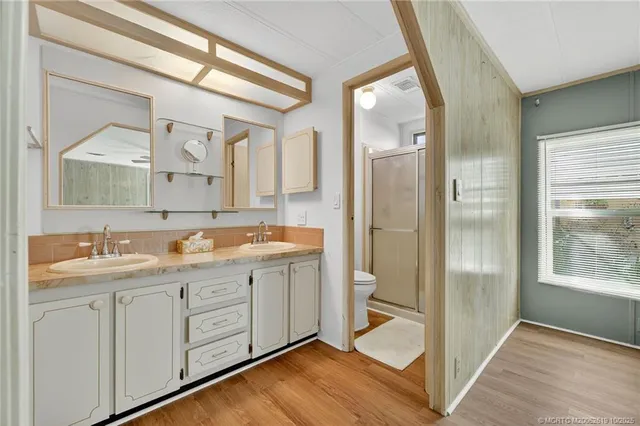 a spacious bathroom with a double vanity sink a mirror and a shower