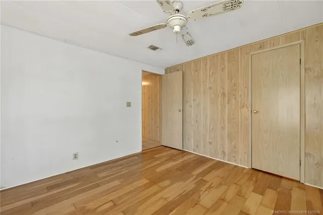 wooden floor in an empty room with a chandelier fan