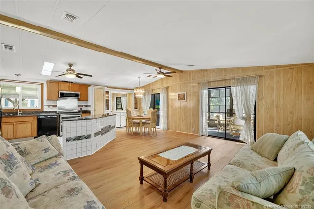 a living room with furniture wooden floor and kitchen view