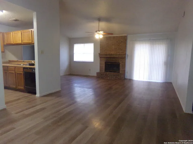 an empty room with wooden floor fireplace and windows