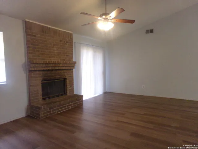 a view of empty room with wooden floor and fireplace