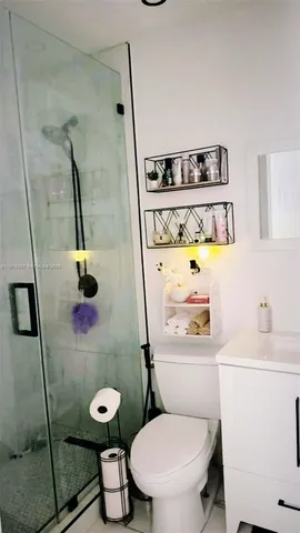 a white toilet sitting next to a bathroom sink and a shower