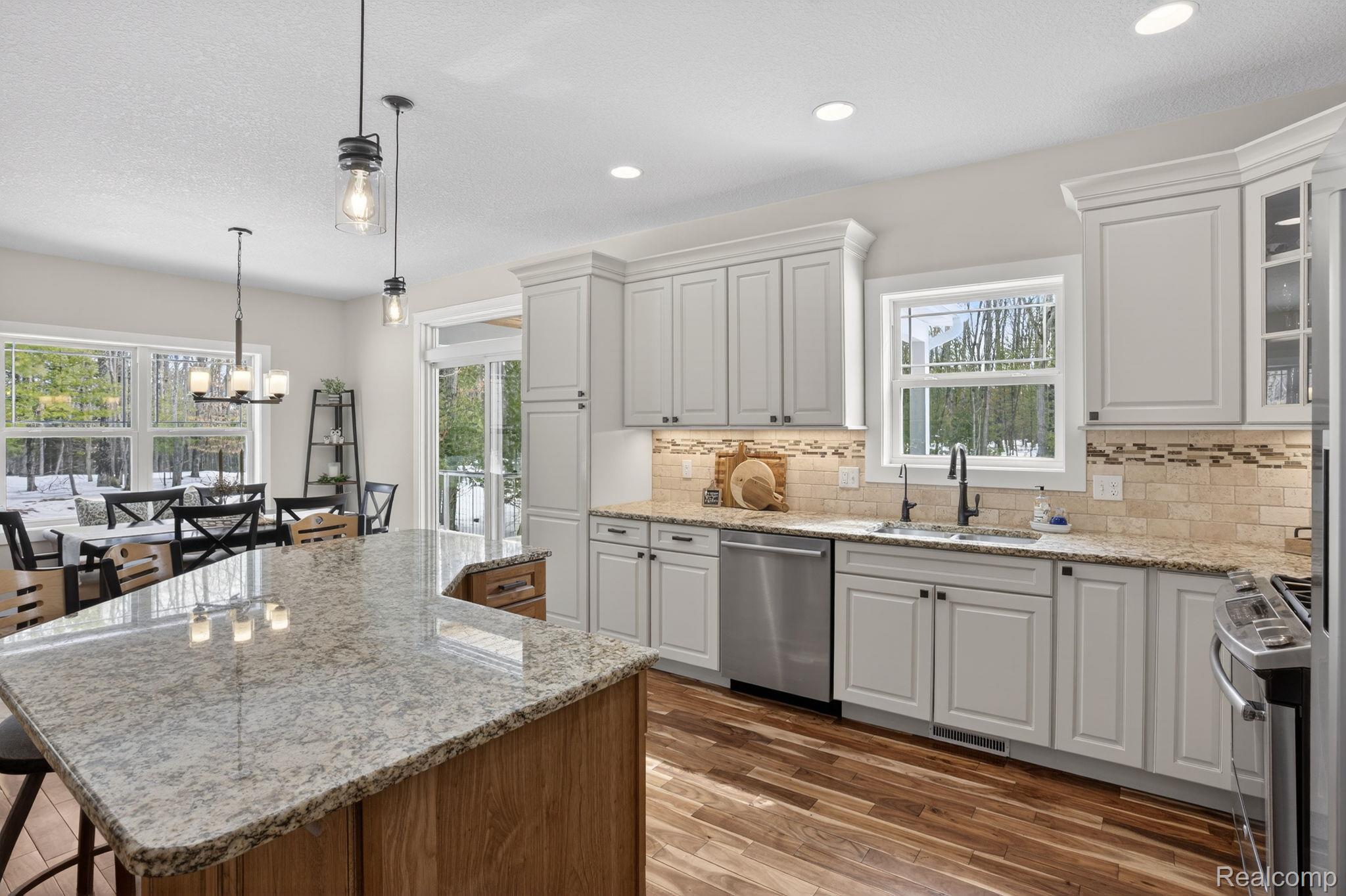 101 Highview Road Traverse City, MI 49696 - Photo 32 of 88 Kitchen with light stone countertops, glass fronted cabinets, dark wood-type flooring, and a center island