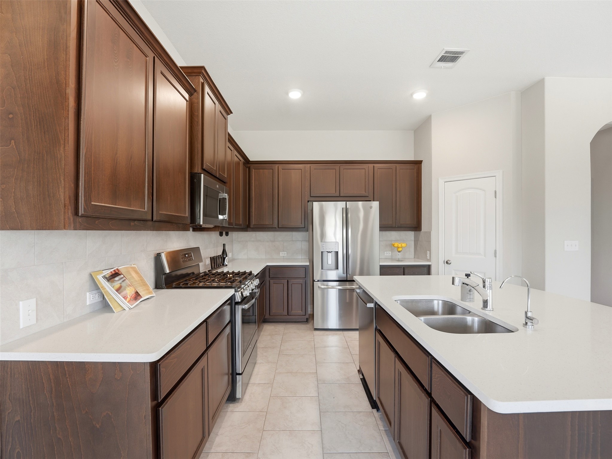 2132 Ringstaff Road Leander, TX 78641 - Photo 14 of 39 Culinary adventures await in this modern kitchen featuring rich cabinetry and a central island with dual sinks.