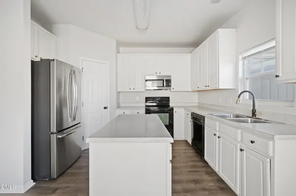 a kitchen with stainless steel appliances a refrigerator sink and white cabinets