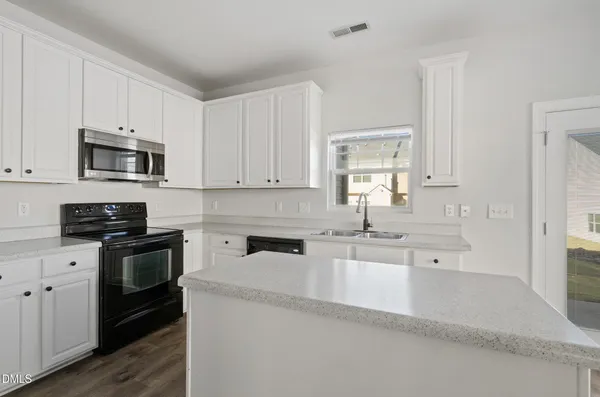 a kitchen with granite countertop white cabinets and stainless steel appliances