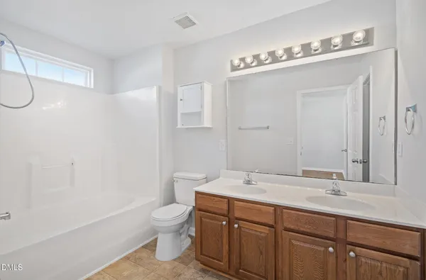 a bathroom with a double vanity sink toilet mirror and shower